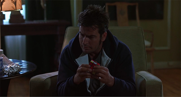 Screencap of Charlie fiddling around with a Rubik's Cube .