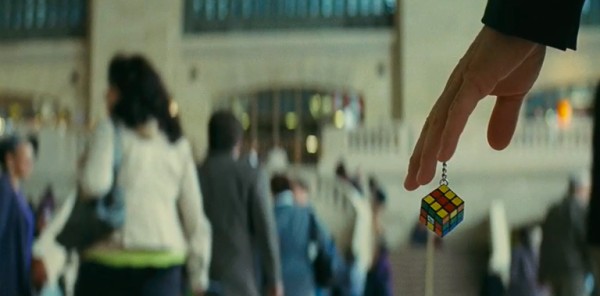 Screencap of Ray's hand, holding a Rubik's cube keychain.