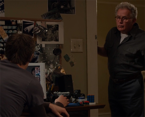 Uncle Ben standing in the doorway, next to a desk with lying on it: a Rubik's Cube.