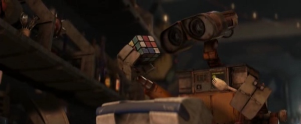 Robot WALL·E has eyes like a binocular. He looks interested with them at a Rubik's cube.