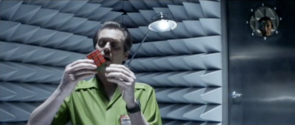 Screencap of Rockhound, holding a solved Rubik's cube in his hands.