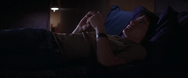 Screencap of Donnie Darko, playing with a Rubik's cube while lying in bed.